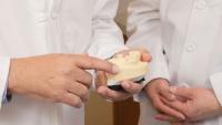 dentist's hands holding set of fake teeth